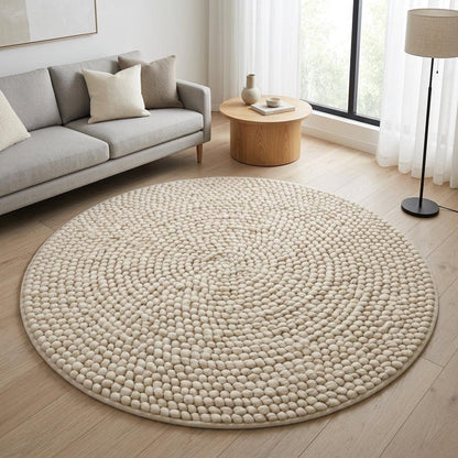 Round Chunky Wool Rug in cream ivory, with a thick handwoven surface of small raised pebble-like loops and a bound edge.