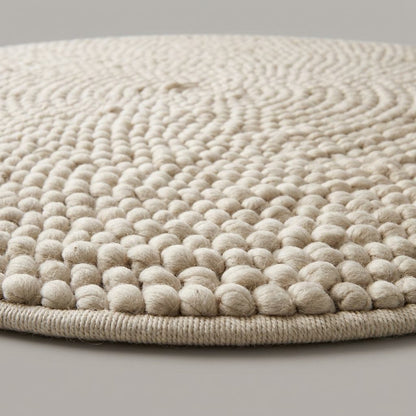 Chunky Wool Rug in cream ivory wool with a thick, handwoven pebble texture arranged in concentric spiral rings and finished edges.