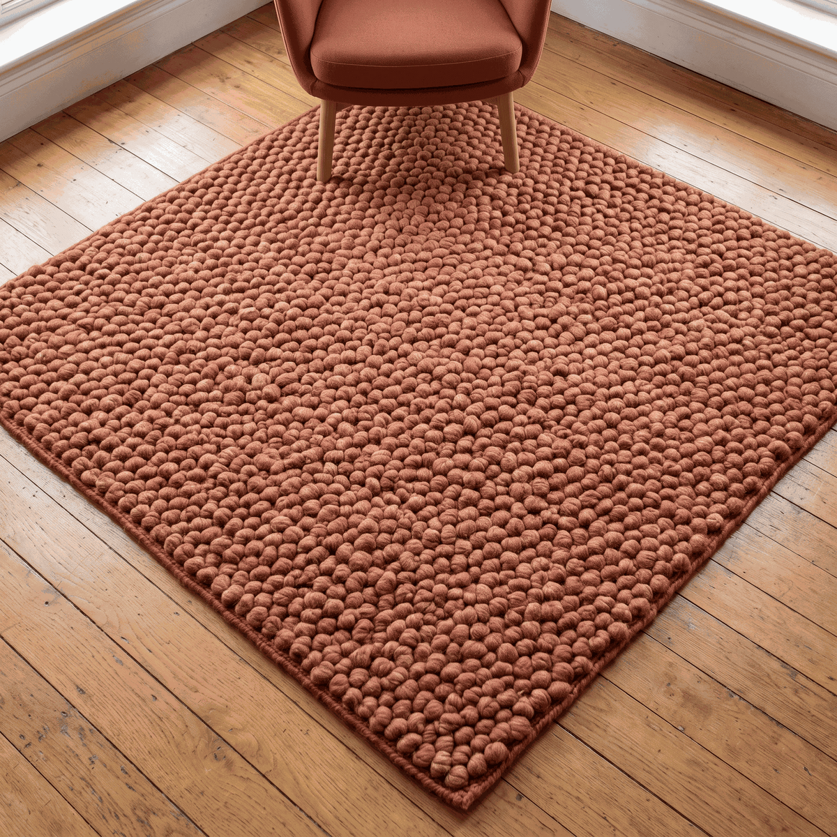 Chunky Wool Rug in rust terracotta with a thick, handwoven pebble texture and rounded rectangular shape