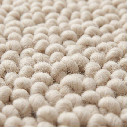 Handmade chunky wool rug with thick textured loops in neutral tones for cozy minimalist home decor