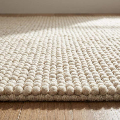 Handmade chunky wool rug with neutral tones and thick textured loops for cozy minimalist Scandinavian decor