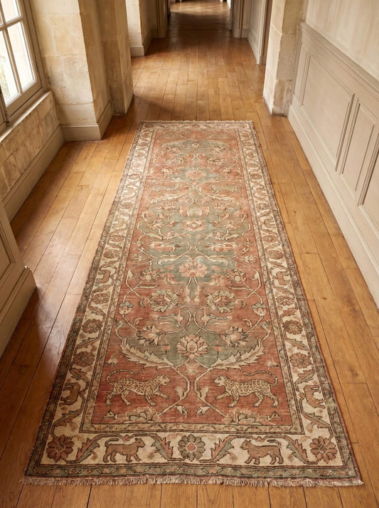 Hand knotted Oushak runner rug with vintage floral and animal motifs in dusty rose and sage green wool