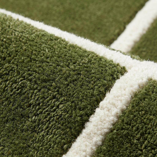 Close up of hand tufted wool rug showing dense plush pile with carved cream geometric lines on olive green background __etsy:7790035076