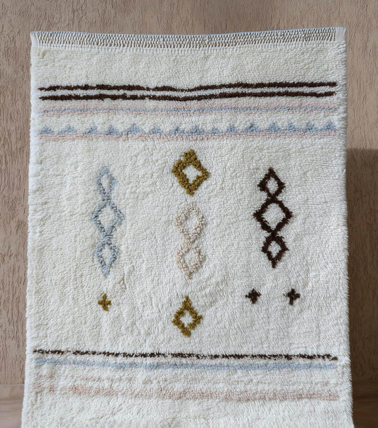 Hand-woven wool rug with pastel Moroccan diamond pattern in blush pink and powder blue on cream background for boho home decor
