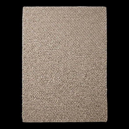 Handmade chunky wool rug with neutral pebble weave in Scandinavian minimalist Japandi living room setting