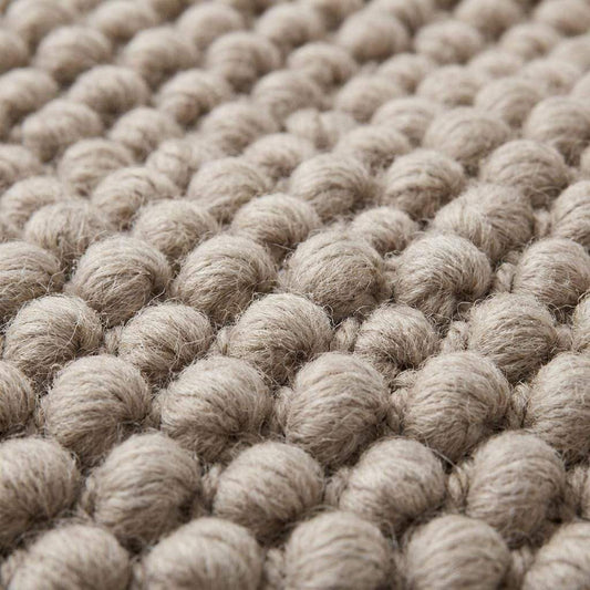 Handmade chunky wool rug with neutral pebble weave in Scandinavian minimalist Japandi style for cozy living room decor