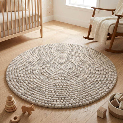 Handmade round wool felt ball rug with neutral pebble texture for Scandinavian nursery decor
