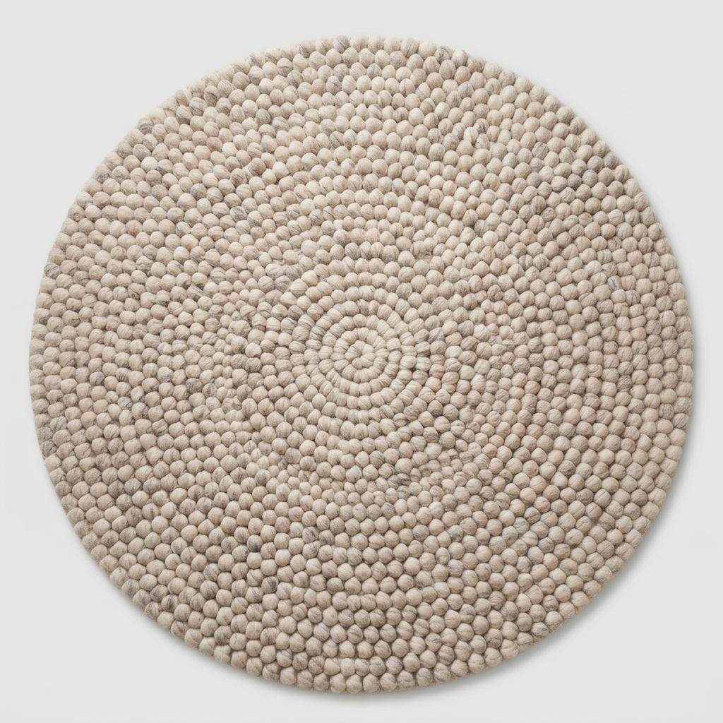 Handmade round wool felt ball rug with pebble texture in neutral Scandinavian nursery decor colors
