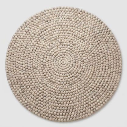 Handmade round wool felt ball rug with pebble texture in neutral Scandinavian nursery decor colors