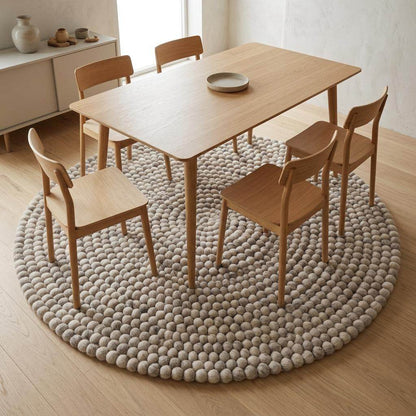 Handmade round wool felt ball rug with neutral pebble design for Scandinavian nursery decor