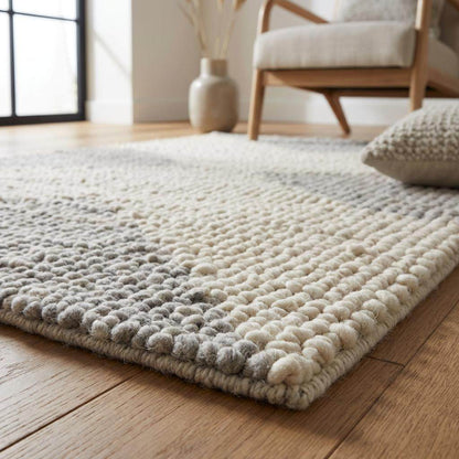 Handwoven chunky wool rug in neutral cream, beige, and gray tones with a subtle geometric pattern for Scandinavian and minimalist interiors
