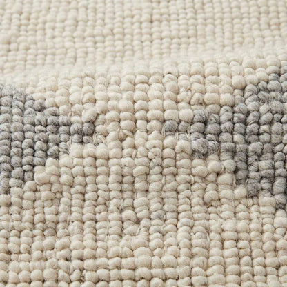 Handwoven chunky wool rug in neutral cream, beige, and gray tones with subtle geometric pattern for Scandinavian and minimalist interiors