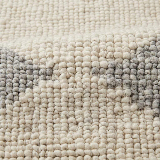Handwoven chunky wool rug in neutral cream, beige, and gray tones with subtle geometric pattern for Scandinavian and minimalist interiors