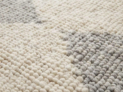 Handwoven chunky wool rug in neutral cream beige gray tones with subtle geometric pattern for Scandinavian minimalist home decor