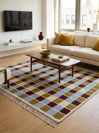 Handwoven flatweave checkered rug with mustard, dusty blue, burgundy, and ivory geometric grid pattern in modern living room setting