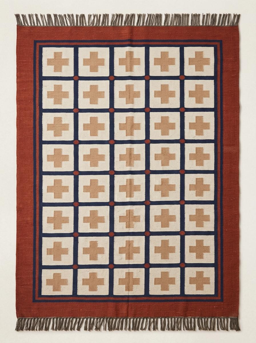 Handwoven flatweave wool rug with Southwestern cross geometric design in rust and navy colors for living room