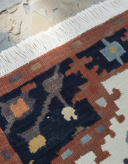 Handwoven Southwestern Kilim rug with cream, rust, navy geometric patterns and fringed edges