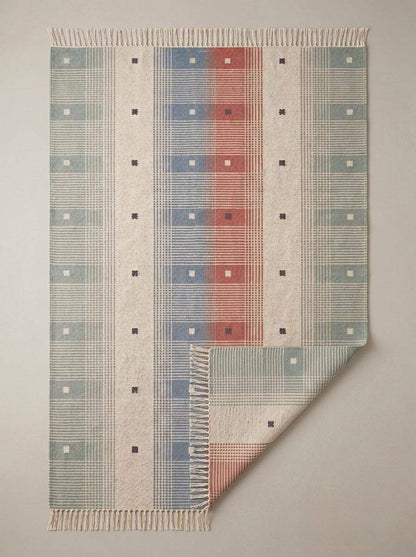 Handwoven tartan flatweave rug in sage green and terracotta with modern Scandinavian plaid design and tassel fringe
