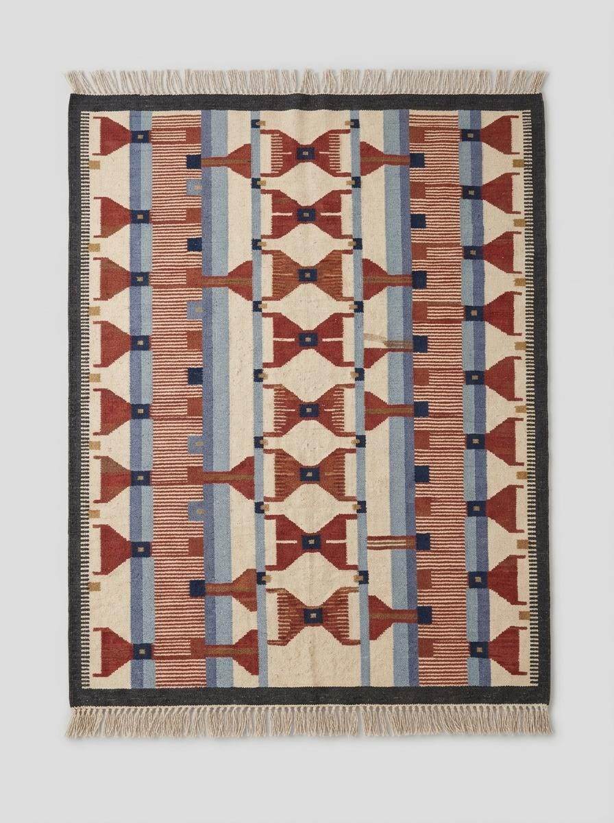 Handwoven wool flatweave rug with geometric kilim design in terracotta, blue, and ivory colors for living room decor
