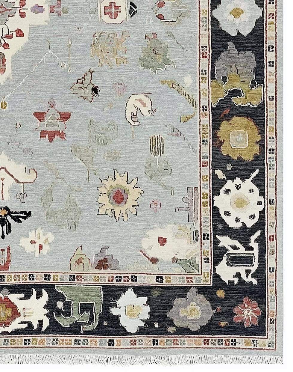 Light blue Oushak rug with navy border and floral medallion design, hand-tufted wool carpet.