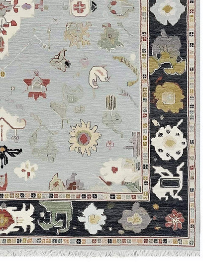 Light blue Oushak rug with navy border and floral medallion design, hand-tufted wool carpet.