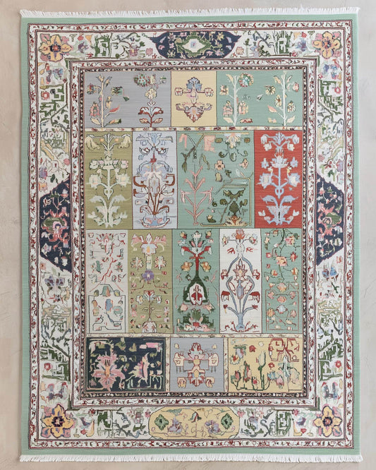 Pastel floral patchwork rug with botanical tile design and fringed edges in soft mint, sage, and navy tones
