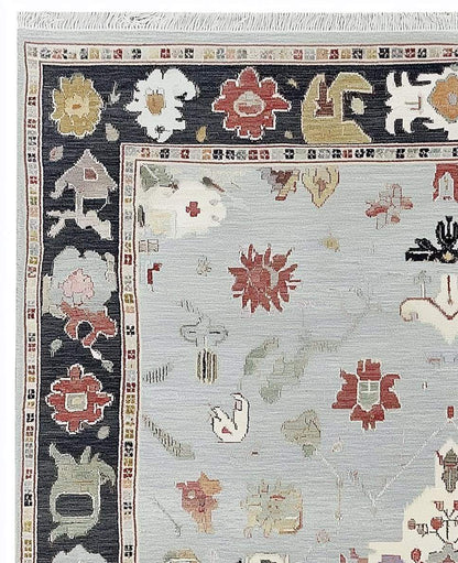 Light blue Oushak rug with navy border and floral medallion design, hand-tufted wool carpet for modern classic decor