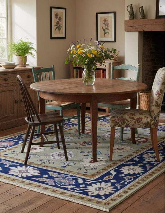 Top view of sage green floral area rug with navy border and ivory accents on stone floor