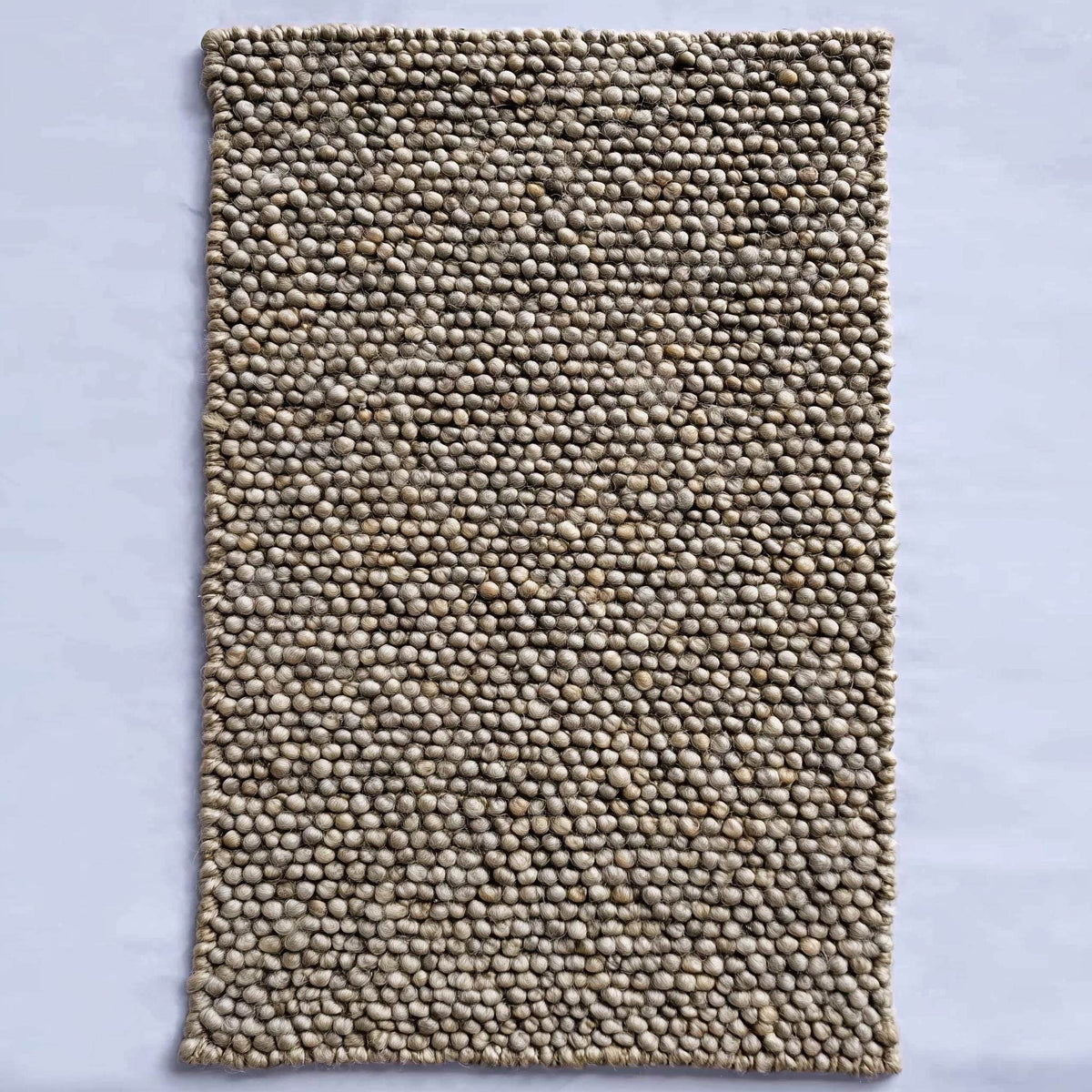 Handmade textured wool mat in natural beige pebble design for cozy modern home decor