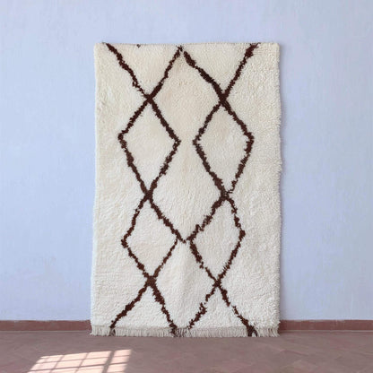 Handmade Moroccan shag rug with ivory background and dark brown diamond pattern, boho minimalist accent.