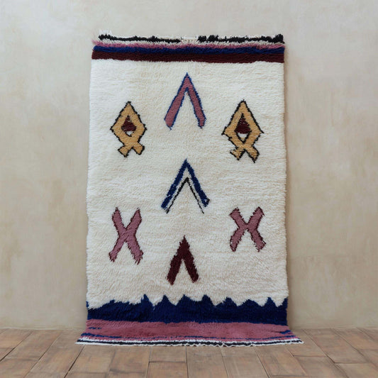 Hand-woven boho Moroccan wool rug with tribal diamond patterns in ivory, navy, mauve, and mustard gold
