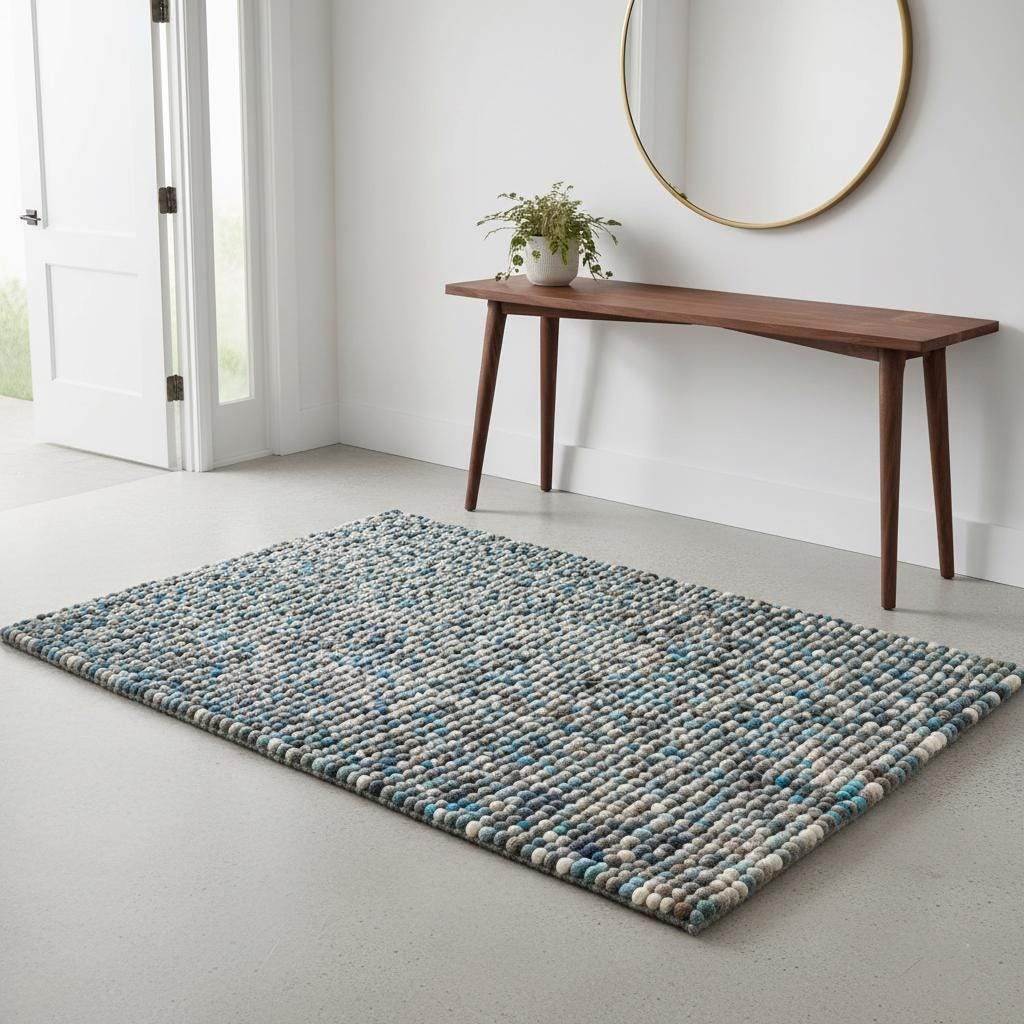 Handcrafted felt ball rug in teal, beige, and grey wool with pebble texture and cozy artisanal design