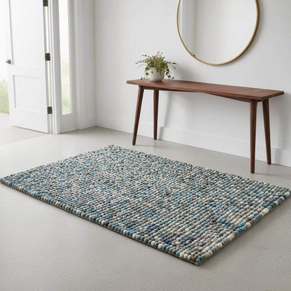 Handcrafted felt ball rug in teal, beige, and grey wool with pebble texture and cozy artisanal design