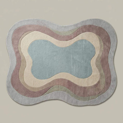 Abstract sculptural wool rug with curved edges and muted colors on wood flooring, handmade tufted carpet for contemporary decor.