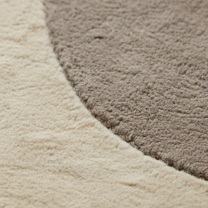 Close-up view of abstract neutral rug texture highlighting soft woven fibers, plush surface, and clean craftsmanship, showing the quality and comfort of the modern minimalist area rug.