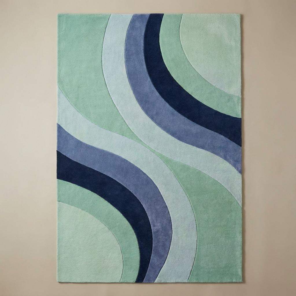 Contemporary mint and blue curved-pattern rug under a navy armchair, perfect for modern or mid-century home décor.