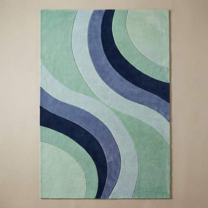 Contemporary mint and blue curved-pattern rug under a navy armchair, perfect for modern or mid-century home décor.