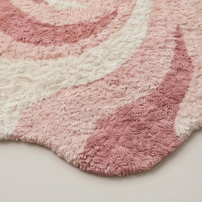 Pink abstract rug with irregular shape and wavy swirl pattern in soft plush shag material