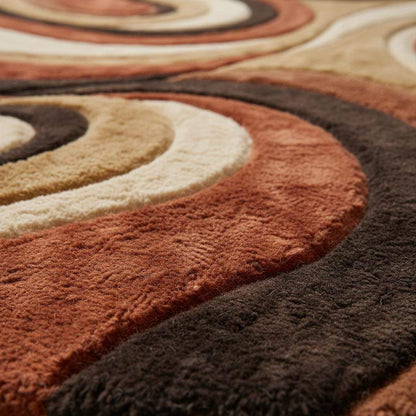 Close-up of plush shag rug texture showing dense high-pile fibers, sculpted abstract swirl pattern, and layered earth tone colors that highlight softness, depth, and quality craftsmanship.