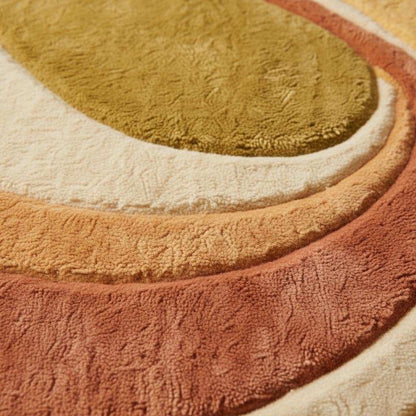 Close-up of tufted abstract rug showing dense pile texture, soft fibers, smooth color transitions, and high-quality craftsmanship in earthy mustard and terracotta tones.