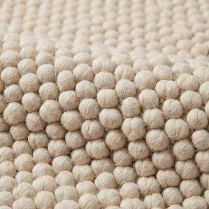 Handwoven chunky wool pebble rug in cream with textured pebble design, ideal for minimalist Scandinavian home decor