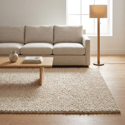 Handwoven chunky wool pebble rug in neutral cream with textured fibers for cozy minimalist Scandinavian decor