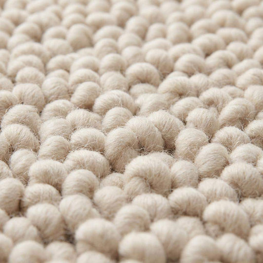 Handmade chunky wool rug with thick textured loops in neutral tones for cozy minimalist home decor