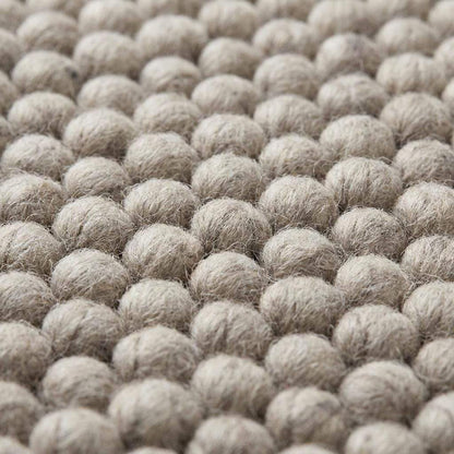 Chunky wool area rug in neutral beige with thick textured weave for cozy minimalist living room decor