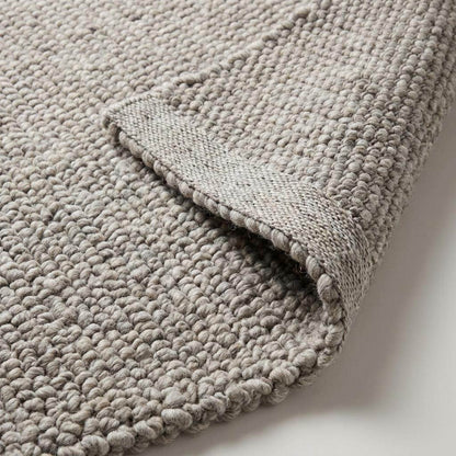 Chunky wool area rug in neutral beige with thick textured weave for cozy minimalist living room decor