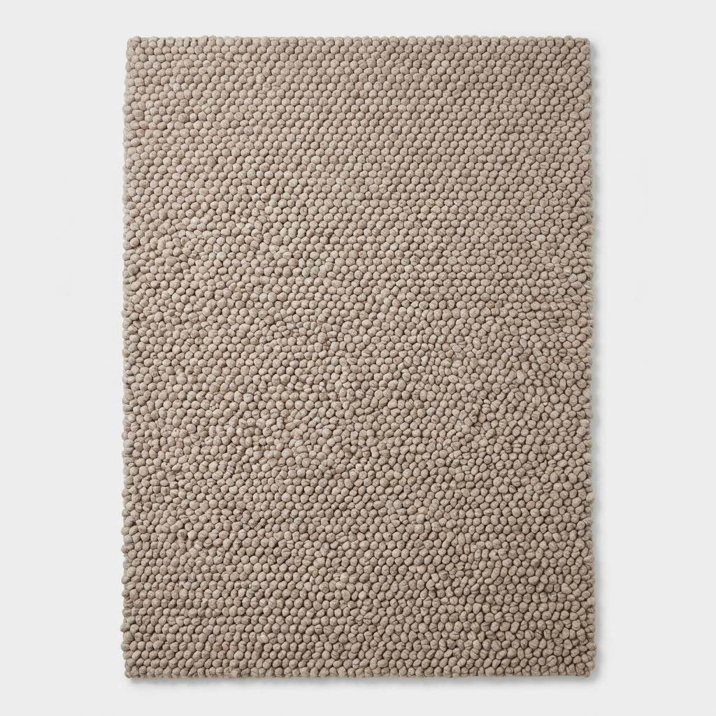 Handmade chunky wool rug with neutral pebble weave in Scandinavian minimalist Japandi living room setting