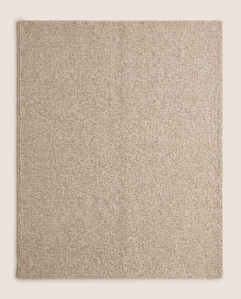Chunky wool loop rug in neutral beige on wooden floor showcasing textured handmade cozy minimalist area rug