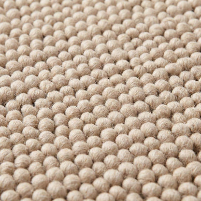 Chunky wool pebble rug in neutral beige with textured handwoven design for minimalist modern living room decor