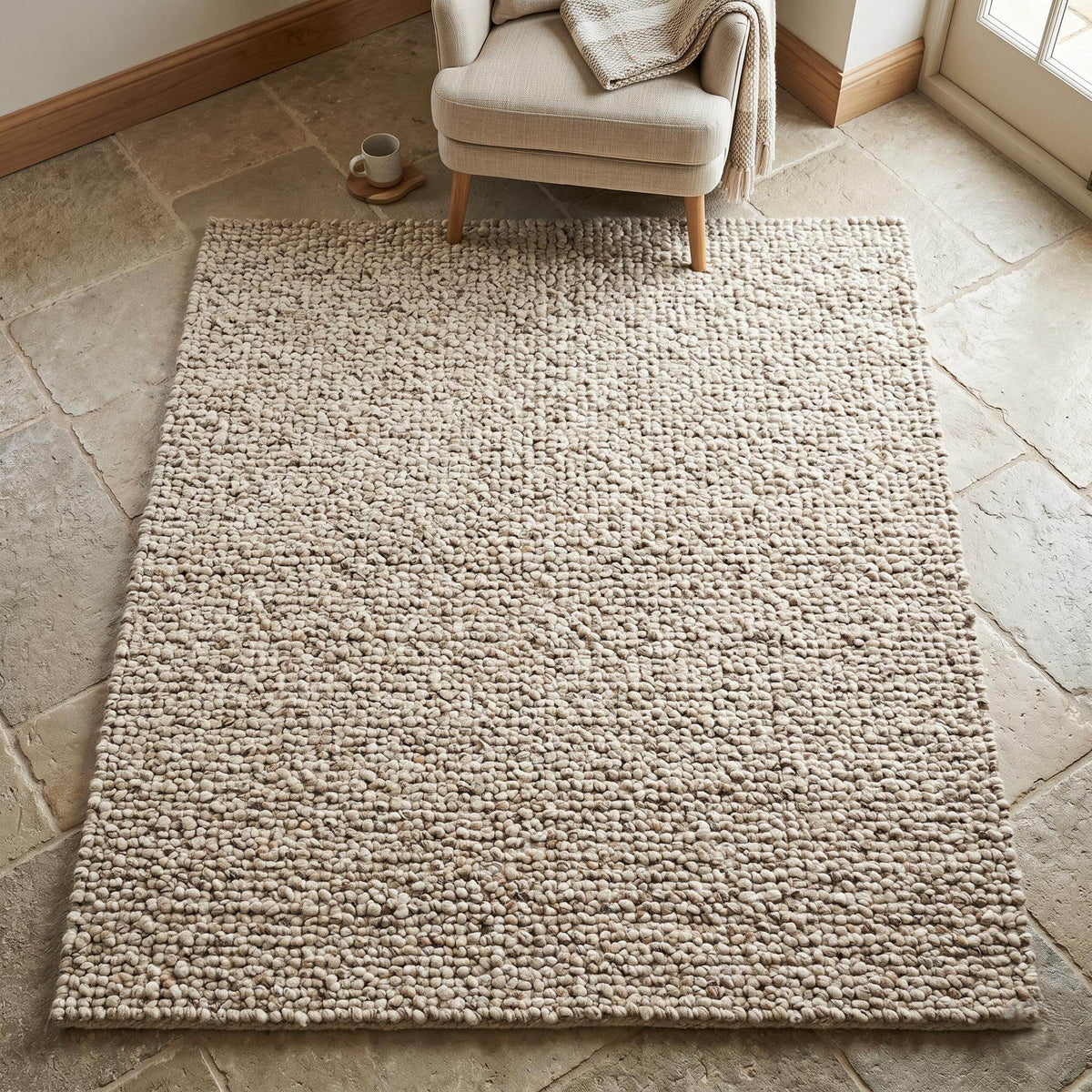 Handwoven chunky wool rug with natural beige pebble texture in Scandinavian living room interior