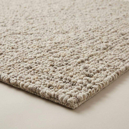 Handwoven chunky wool rug with natural beige pebble texture in a Scandinavian living room setting